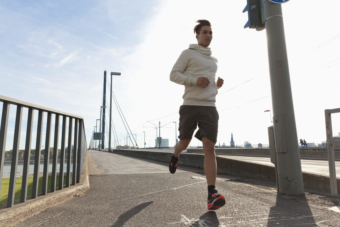 Jogger läuft am sonnigen Morgen über die Rheinkniebrücke in Düsseldorf.