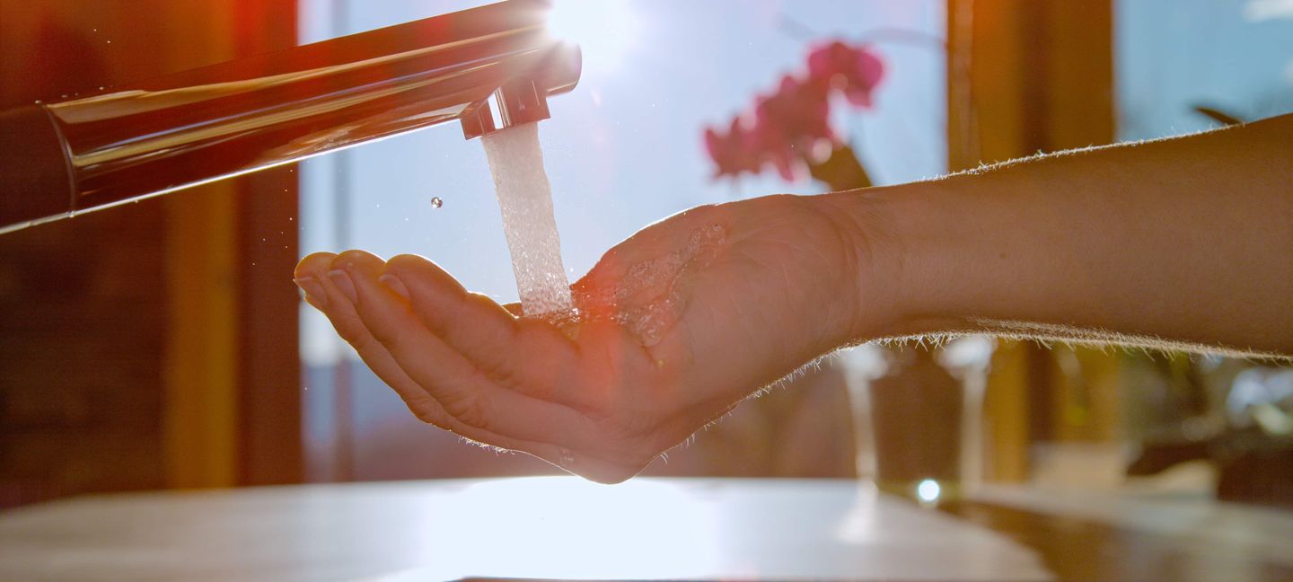 Eine Frau füllt ein Glas mit Wasser am Wasserhahn